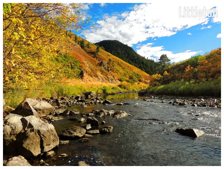 The hilly slopes on the South Platte River during the fall, large rocks, and stones in the river below